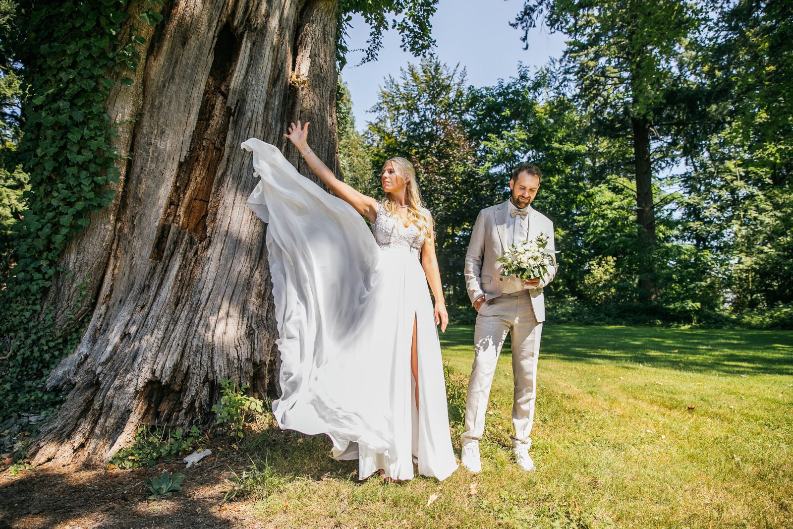 Brautpaar vor altem Baum mit wehendem Brautkleid – Hochzeitsfotograf | Hochzeitsvideograf NRW